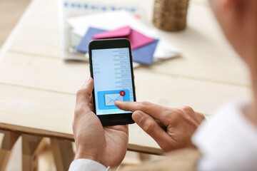 Young man with mobile phone checking his e-mail at home, closeup