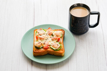 熱々のピザトーストが青い皿の上に、ホットカフェオレとともに