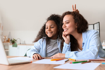 Obraz premium African-American little girl with her mother using laptop at home