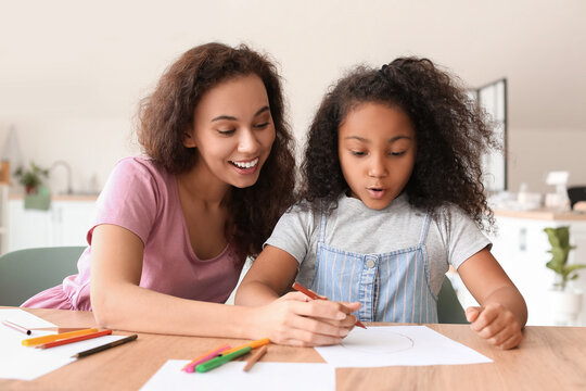 African-American little girl with her mother drawing at home