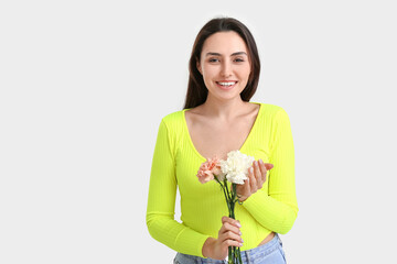 Fototapeta na wymiar Young woman with beautiful carnation flowers on light background