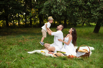 Happy family having picnic outdoors with their cute son