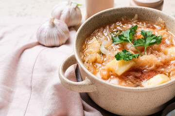 Pot with tasty sauerkraut soup on light background, closeup
