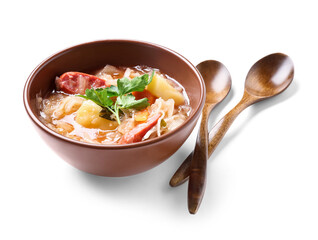 Bowl with tasty sauerkraut soup and spoons on white background