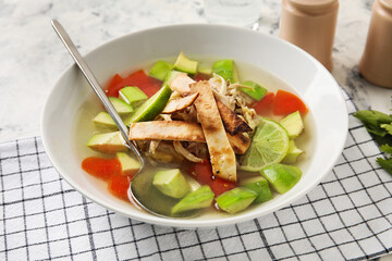 Bowl of tasty Sopa de Lima soup on light background