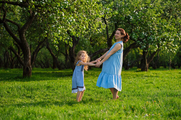 Naklejka na ściany i meble nature scene with family outdoor lifestyle. Mother and little daughter playing together in a park. Happy family concept. Happiness and harmony in family life.