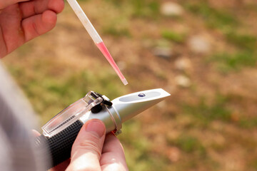 the winemaker applies a drop of grape juice with a pipette to the prism of a refractometer to...