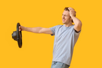 Stressed young man with steering wheel on color background