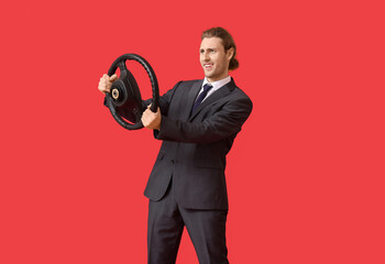Fototapeta premium Young businessman with steering wheel on color background