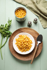Plate with corn kernels and spices on color wooden background