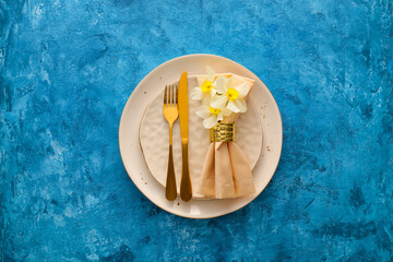 Beautiful table setting with narcissus flowers on color background