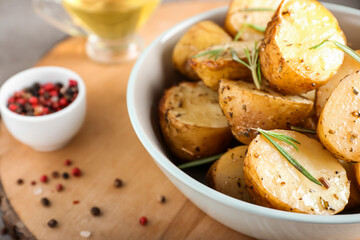 Bowl with baked potatoes and rosemary on table