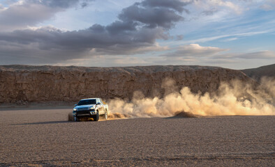 a black car or pickup truck is drifting an sands and splashing dirt on air and around in dasht e...