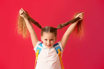 Little schoolgirl with backpack on color background