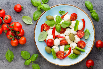 Delicious caprese salad with ripe cherry tomatoes and mini mozzarella cheese balls with fresh basil leaves.