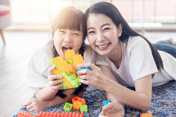 Obraz na płótnie Canvas Enjoy happy love Asian family mother and little cute girl smiling playing with toy building or construction toys at home
