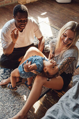 Little girl and her two loving parents inside living room