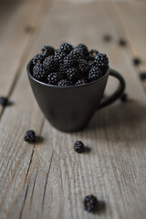 Fototapeta na wymiar blackberries in a black glass on a wooden background