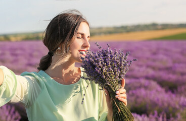 Beautiful young woman taking selfie in lavender field