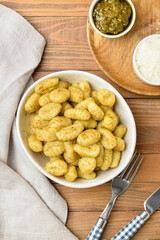 Composition with tasty pesto gnocchi on wooden background