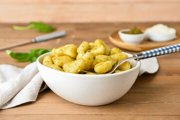 Bowl with tasty pesto gnocchi on wooden background