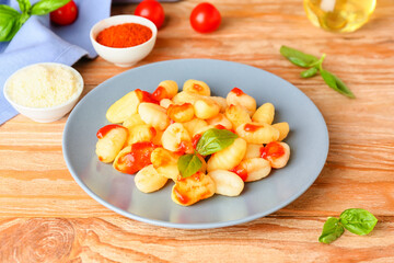 Delicious gnocchi with tomato sauce in plate on wooden table