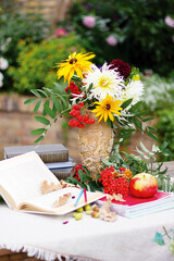 Autumn flowers with book and ashberry. Still-life with apple and flowers.