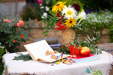 Autumn flowers with book and ashberry. Still-life with apple and flowers.
