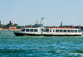 Empty white ferry boat or vaporetto in motion in the Venetian Lagoon on a sunny spring day. Venice,...