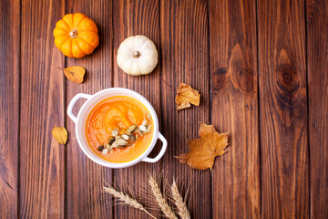 Plate of pumpkin soup on a wooden background. View from above