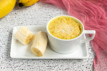 banana muffin in a mug on a plate. Fresh bananas next to homemade muffins. homemade magician cake is cooked in the microwave. Banana dessert, baked goods. High quality photo
