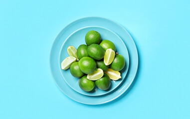 Plate with tasty limes on color background