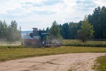 old tracktor plows the field. harvester harvests wheat from a sown agricultural field