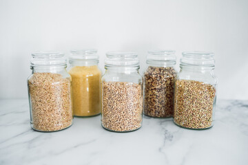 clear pantry jars with different types of grains in them including quinoa rice buckwheat couscous and barley, simple ingredients concept