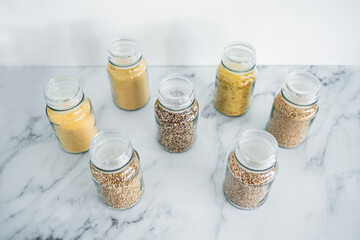 clear pantry jars with different types of grains in them including quinoa rice buckwheat couscous...