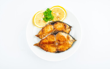 Pan-fried mackerel pieces on a plate on white background