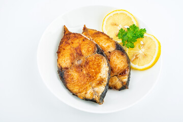 Pan-fried mackerel pieces on a plate on white background