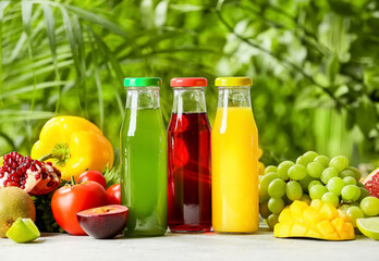 Bottles with healthy juice, fruits and vegetables on table outdoors, closeup