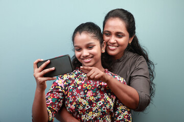 Indian ethnic mother and daughter engaged with a mobile phone