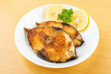 Pan-fried mackerel pieces on a plate on white background