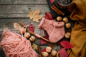 Cute small woolen baby socks, autumn decorations, on dark wooden background