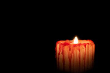Bloody white candle with red streaks burns in darkness night isolated on black. Concept of grief,...