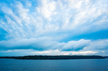 Obraz premium River landscape. Calm water and blue sky with clouds. Trees grow on the nearest shore. There is copy space