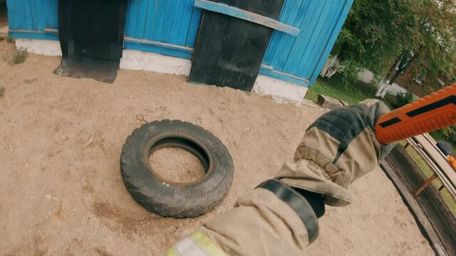 Training of firefighters. A firefighter hits a car wheel with a sledgehammer, developing great physical endurance. Physical activity.