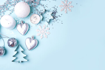 Silver and white christmas decorations on a blue background. Flat lay style