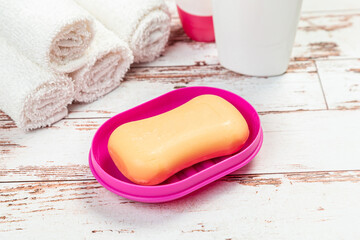 Obraz na płótnie Canvas soap on pink plastic soap dish with towels on white wooden table in bathroom