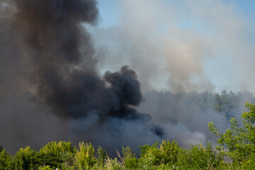 Black toxic smoke from burning plastic in the countryside. Garbage dump in fire polluting the air with harmful gases