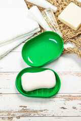 new soap on a green plastic soap dish, on a white wooden background.