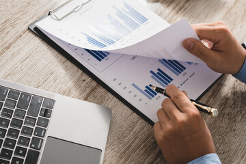 Businessman is deeply reviewing a financial report for a return on investment or investment risk...
