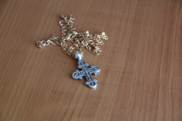 Golden Christian cross on a chain on a wooden shelf